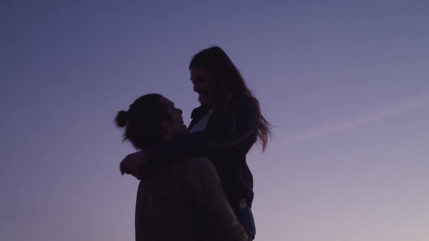 A man and a woman hugging and twirling romantically