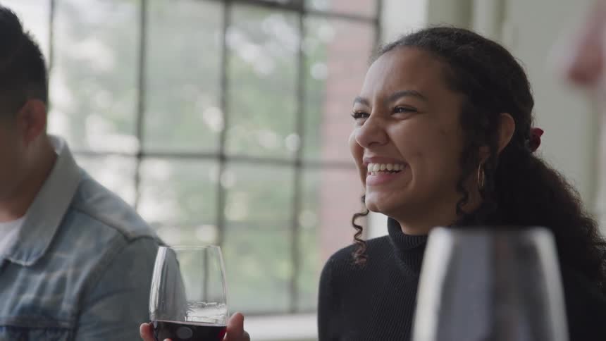 Three people are engaged in conversation while holding glasses of red wine seemingly enjoying a relaxed moment together