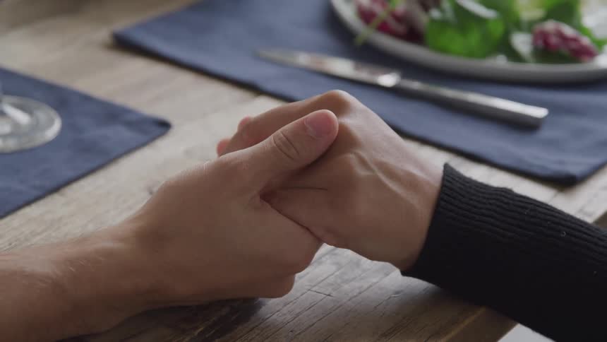 Man and woman holding hands over a table