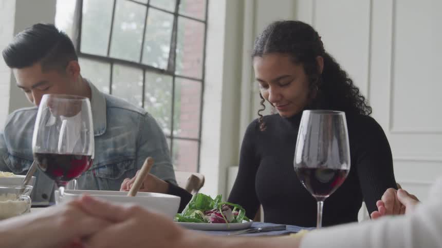 People have their heads bowed in prayer before a meal