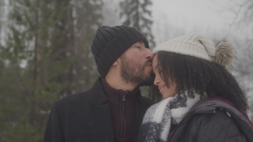 Man kisses woman on the forehead tenderly