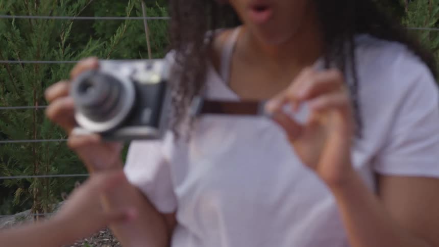 A woman looking at an instant photo she has pulled from her hand held camera as a child trys to grab it away from the woman