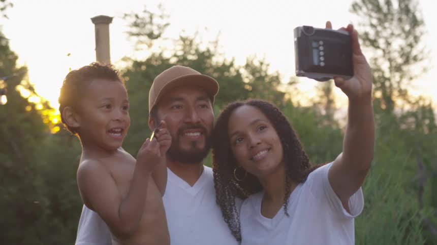 Mom taking a selfie with dad and son outdoors on cell phone