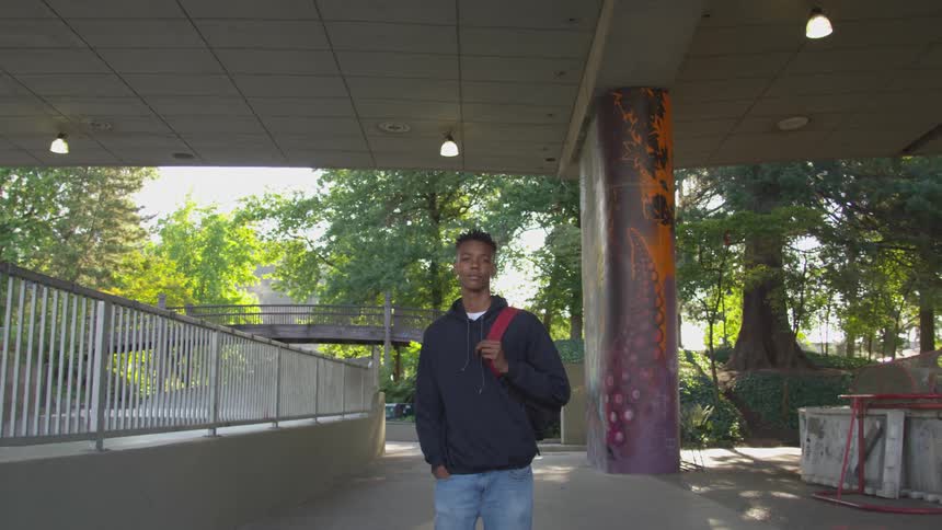A teenager stands on the sidewalk outside