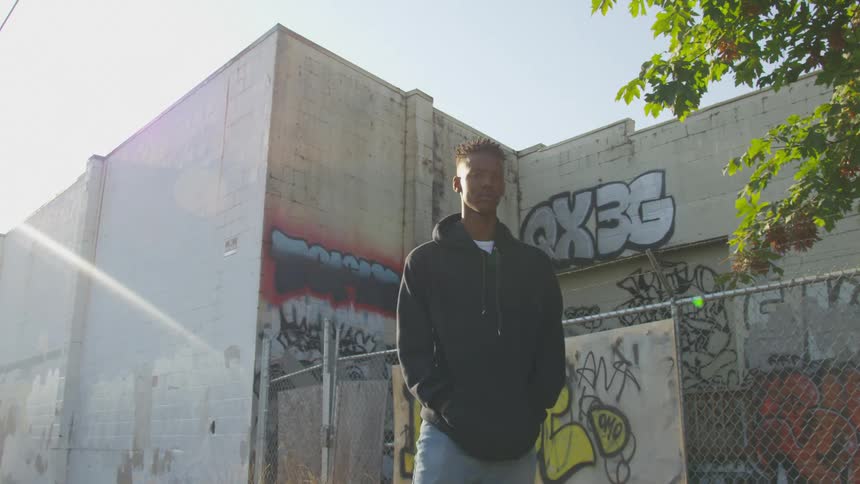 A man is standing outside a building that has graffiti on it