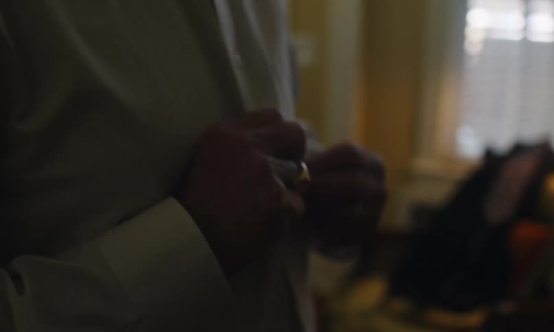 Man buttons his white dress shirt