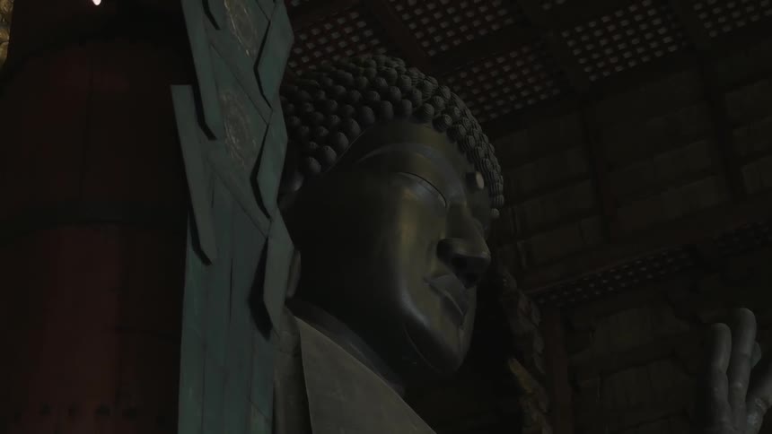 A large statue made of metal is of a person's face
