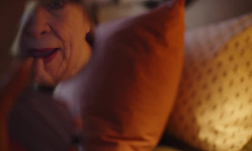 Elderly woman applying makeup by mirroring herself at a small mirror