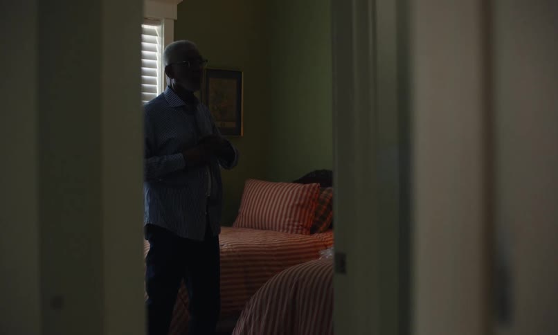 An elderly man is getting dressed in his bedroom