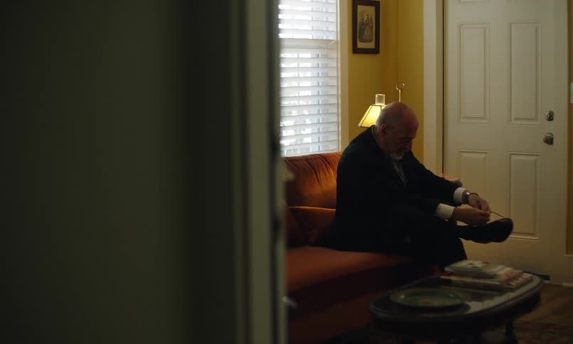 Elderly man trying to tie his shoes