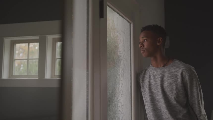 Man sadly looks out the window at the pouring rain