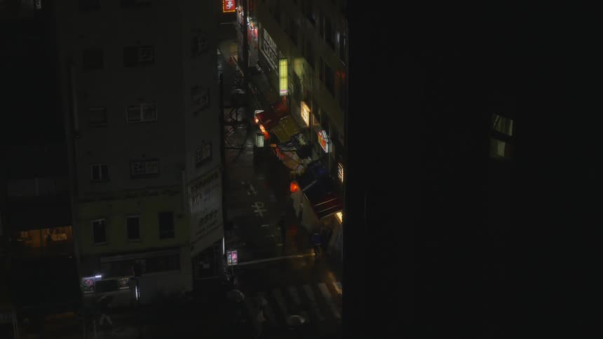People carry umbrellas and walk on a city street at night