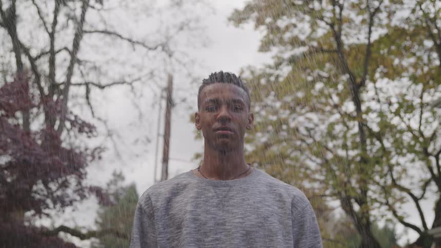 Man in front of trees gets rained on