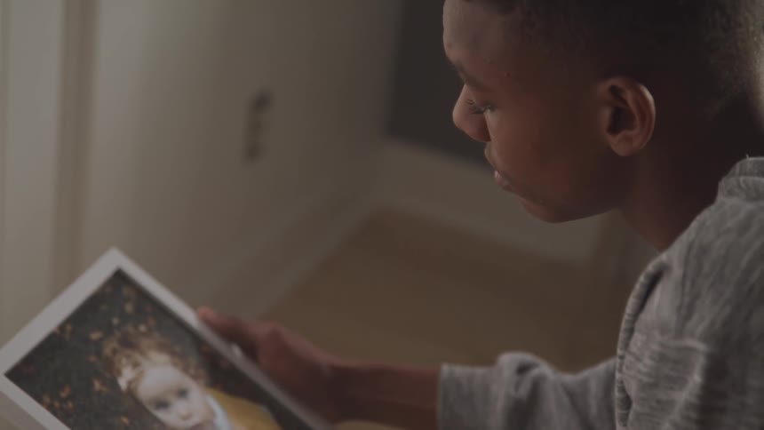 A teenager is looking and examining a photograph