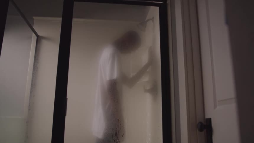 A man is showering with his clothes on