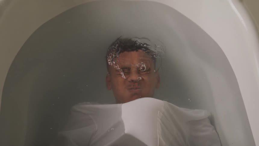 A teenager blows bubbles while submerged underwater in the tub