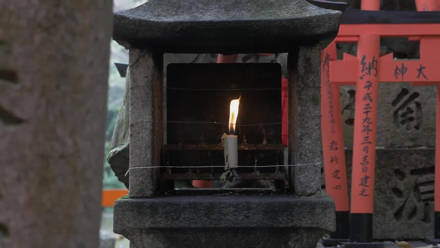 A temple has a lit candle in a stone holder