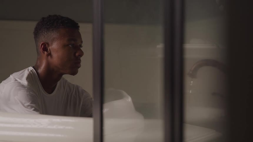 A teenager sits in the bathtub clothed