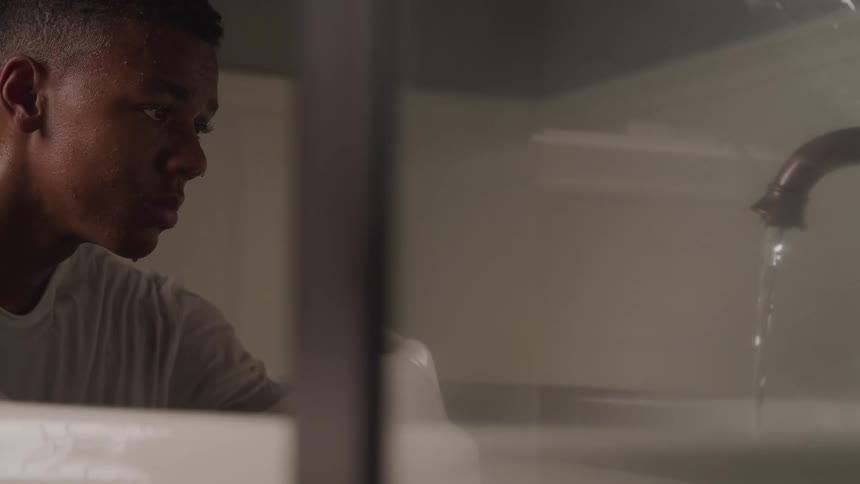 Man looking up at a sink into which water is flowing