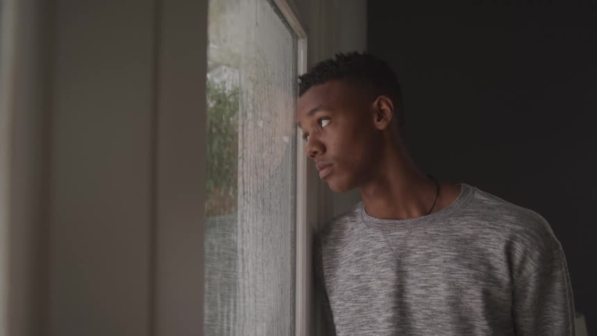 Sad boy with his head leaning against a door