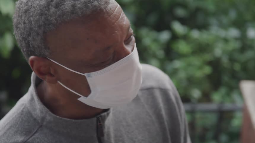 A man wearing a mask is talking to his friends outdoors
