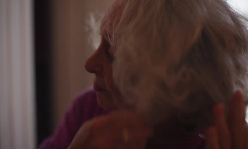 Elderly woman teases her hair using a pick