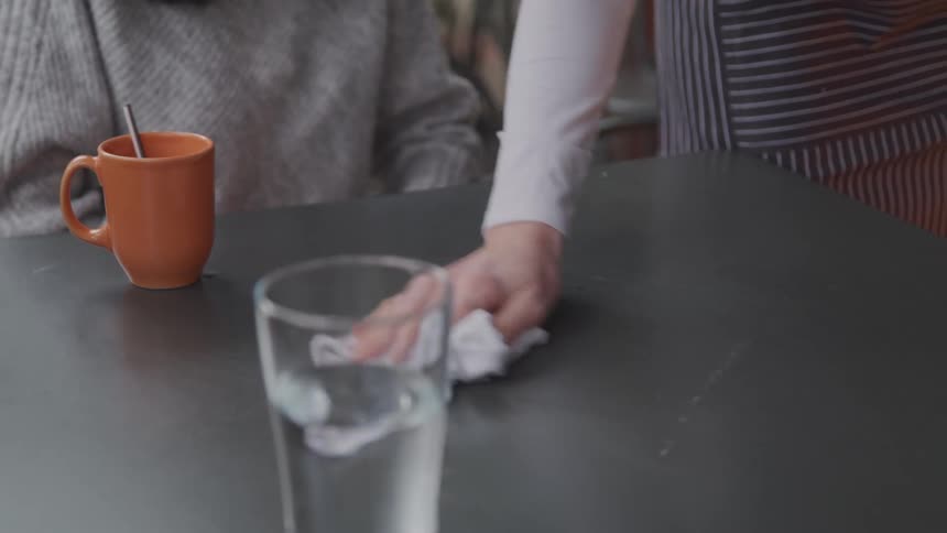 A worker is cleaning the table for a customer at the restaurant