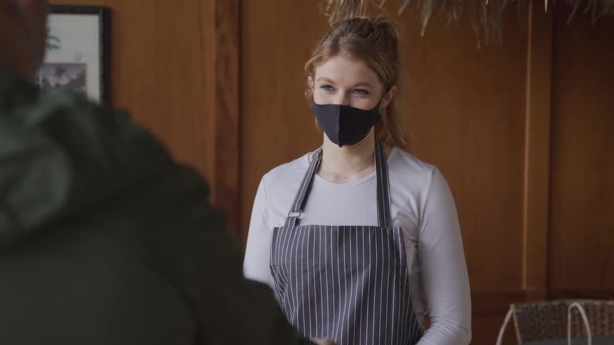 Restaurant worker indicates the takeout bag a male customer should take