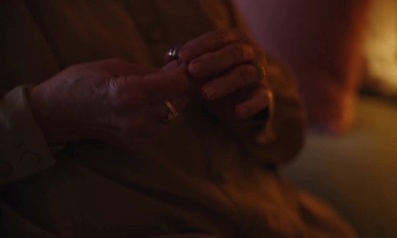 Woman puts two rings on her hand while sitting on her bed