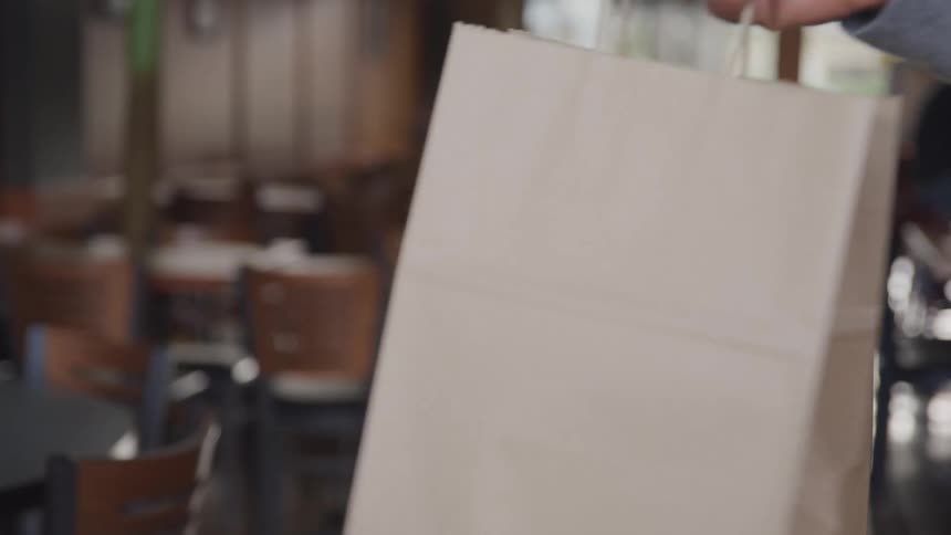 Person points to a paper bag before another person takes it