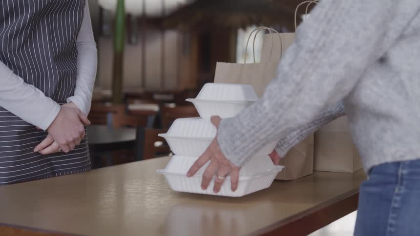 A woman picks up a take out order in the restaurant