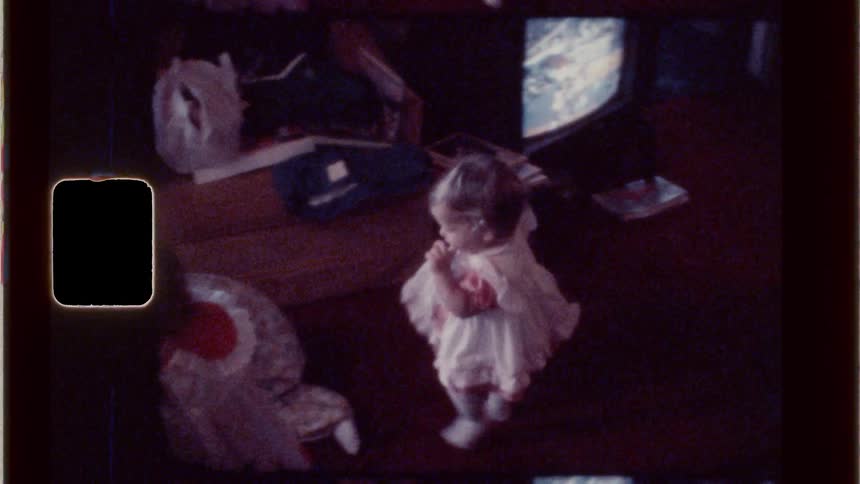 Little girl with her finger in her mouth walking among other children in a room
