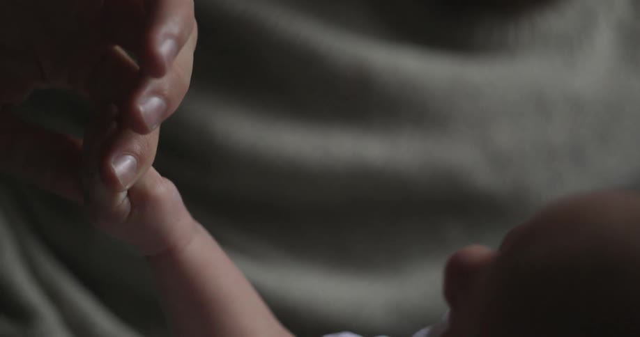 Adult holding an infant's hand