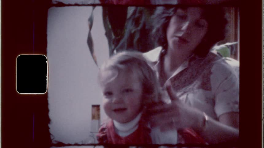 A child jumps around in her parents arms