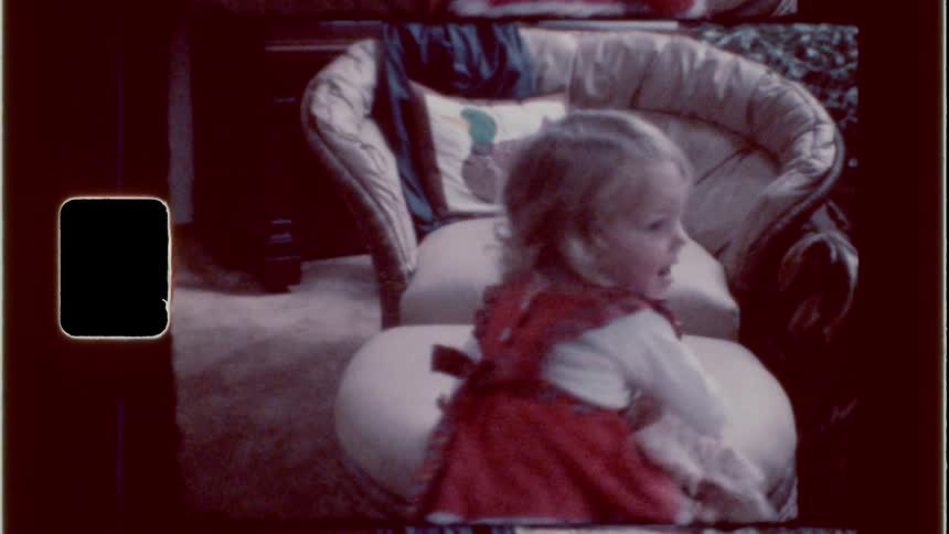Little girl walks cross the room to pick up a doll resting on an ottoman in the living room