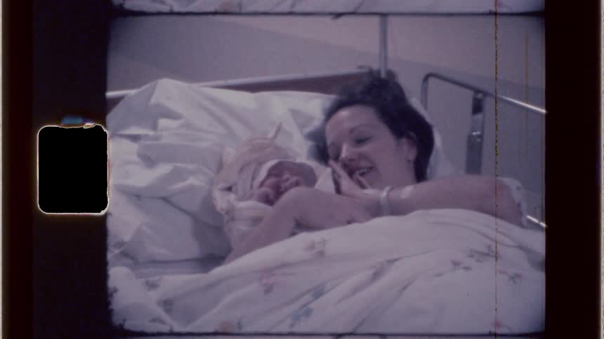 Happy new mom holding newborn in hospital bed after delivery