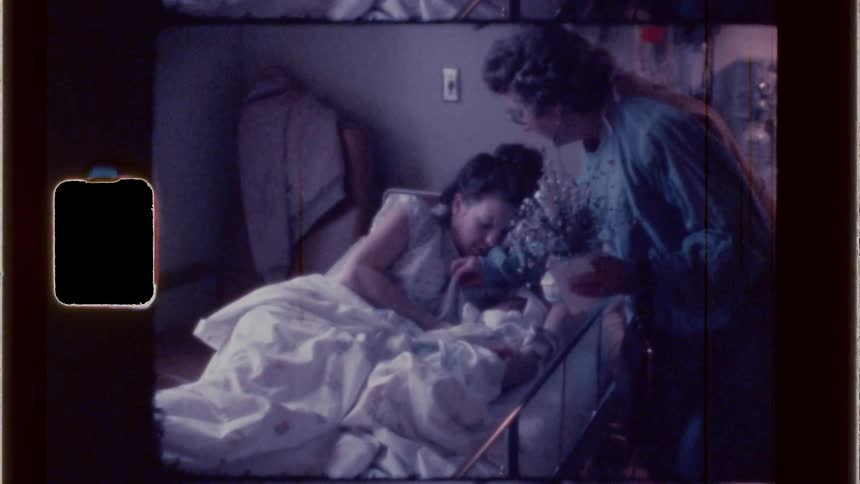 A visitor brings flowers to a woman in the hospital