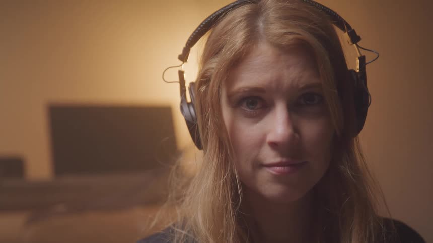A woman is sitting in a room with headphones on