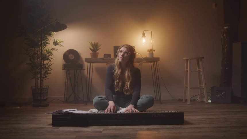 A woman is playing the keyboard on her floor