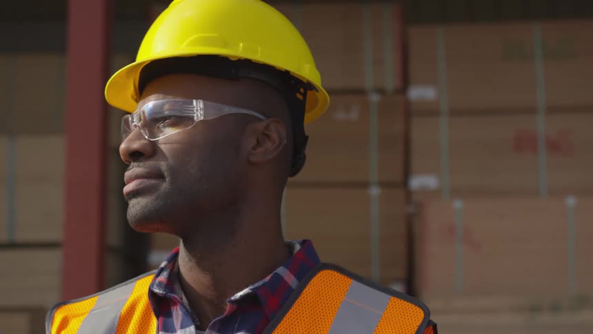 A worker is looking to the side by a warehouse