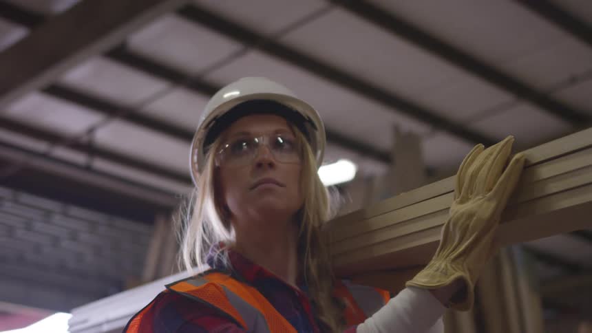 A woman is carrying planks of wood