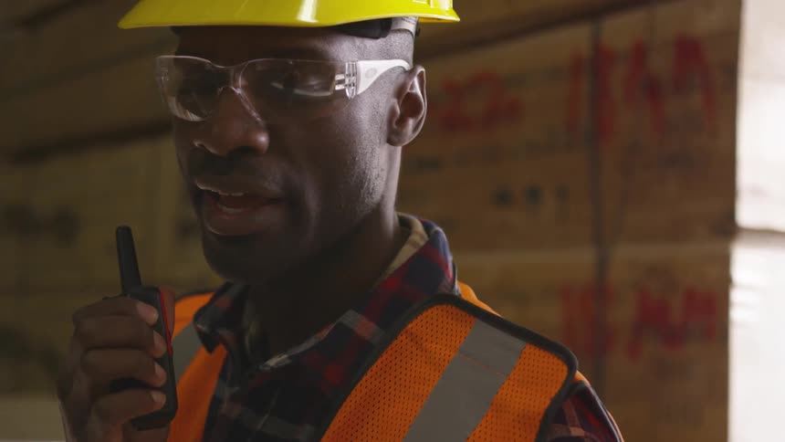A man is using his walkie talkie in the lumber yard