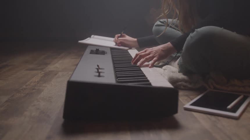 Woman makes musical notations after playing on the piano keyboard