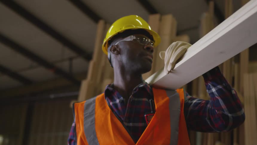 Worker carrying wooden boards on his shoulders