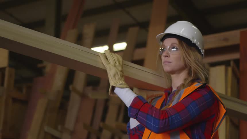 Woman dressed for work carrying wooden boards