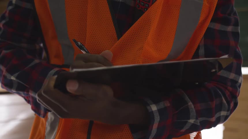 A construction worker is writing on his clipboard
