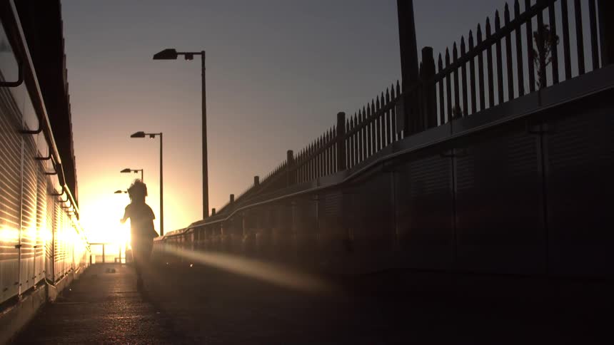 A child runs down a sidewalk at sunset