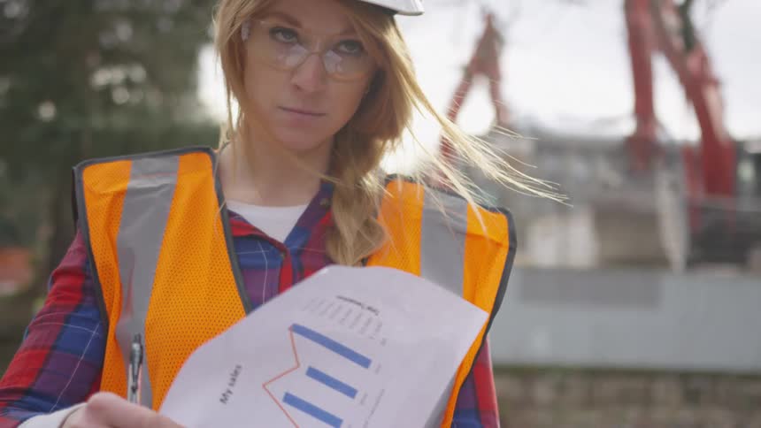 A woman reads paperwork on the construction site