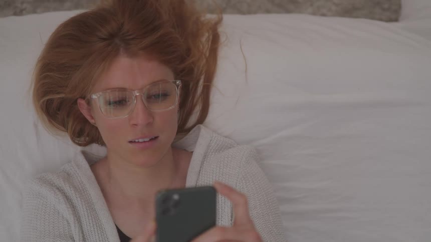 Girl lying in bed typing on cell phone