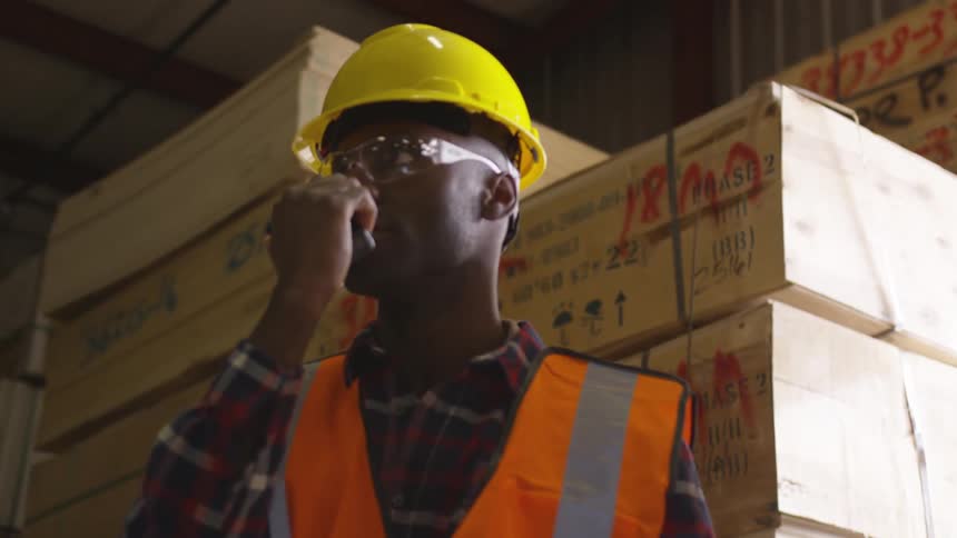 Male worker at a lumber store holds a walkie talkie to his mouth